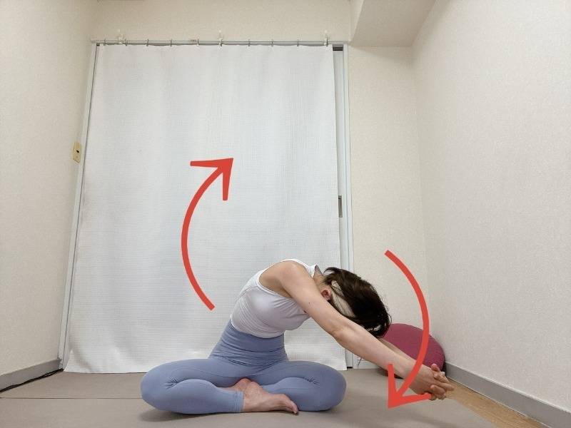 あぐらで座り、両手を組んで頭上に府引き上げて上体を回す背骨のストレッチ