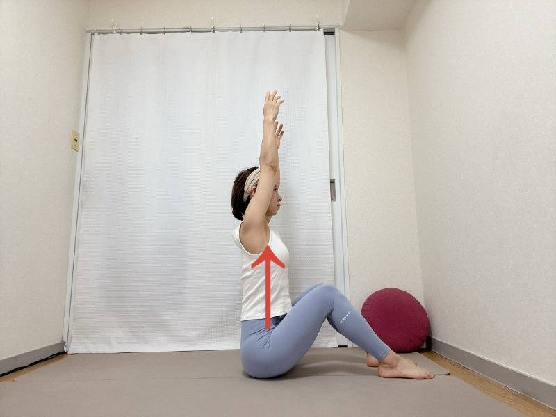 両膝を立てて座り、骨盤を立て背筋を伸ばして両手を頭上に引き上げた体勢
