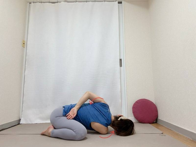 膝を広めに開き、左腕を右脇に通し、右手を背中に回したツイストチャイルドポーズ