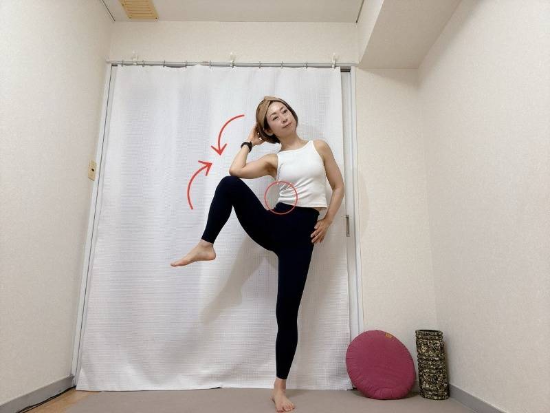 足を腰幅～肩幅程度に開いて立ち、左肘と左膝を体の横で引き寄せる脇腹を引き締めるエクササイズ