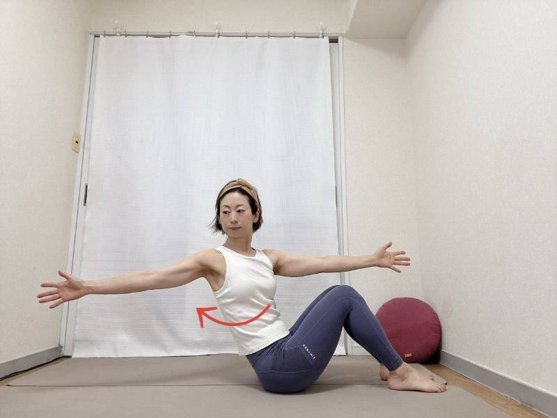 両膝を立て、上体を少し後ろに傾けて座り、右手を前、左手を後ろに伸ばしたツイストエクササイズ