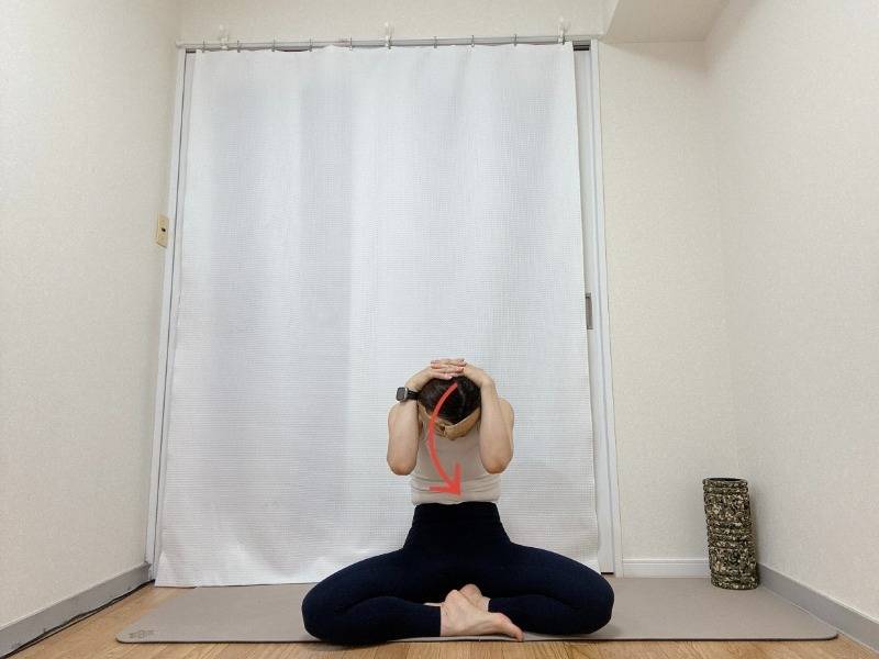 頭の後ろで手を組み、背中を丸めるストレッチ