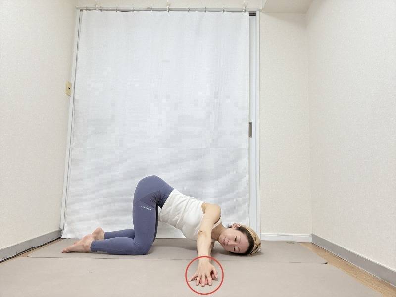 四つ這いから左脇の下へ右腕を通し、右肩と右側頭部を床につける。両手のひらを重ねて押し合いながら、背骨を軽くひねるストレッチ。