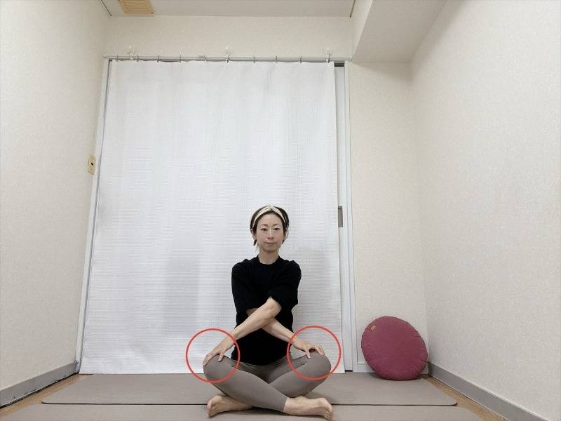 両手を体の前でクロスし、右手を左膝、左手を右膝に置いたあぐらの体勢