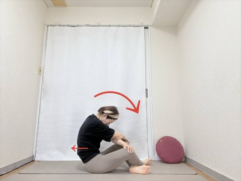 両手を体の前でクロスして膝を掴み、背中を丸めるように重心を後ろに引いたあぐらの体勢