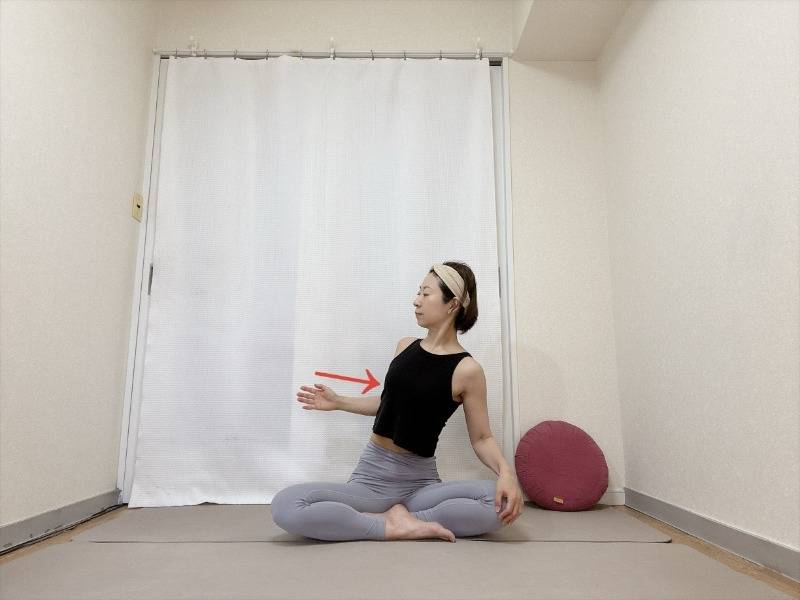 あぐらで座り、横に伸ばした左腕の肘を曲げ、脇を締めながら肩甲骨を寄せるエクササイズ
