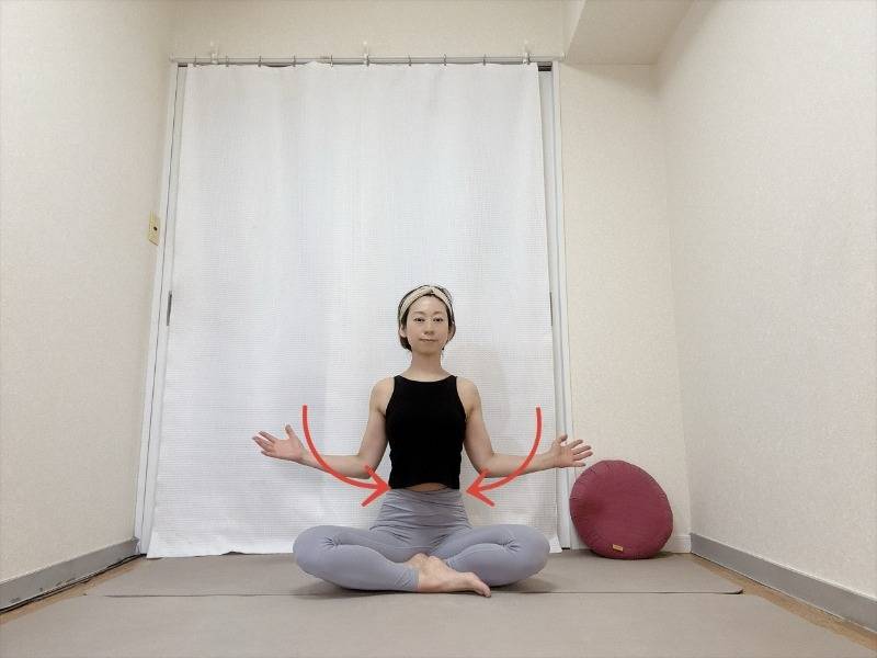 あぐらで座り、腕を肩の高さで伸ばし、肩甲骨を寄せて肘を脇腹に引き寄せるエクササイズ