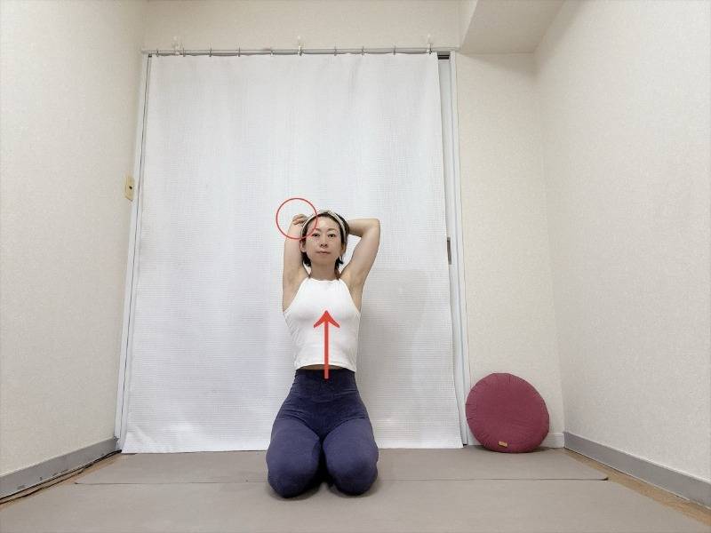 頭の後ろで左肘を右手で掴み、正座で座つた体勢