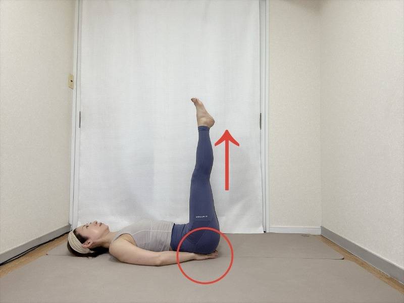 手のひらをお尻の下に敷き、両足を天井に伸ばした仰向けの体勢