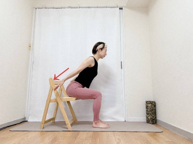 椅子に座り、背筋を伸ばしたまま上体を前に傾け、脇を締めて両腕を斜め後ろに伸ばした体勢