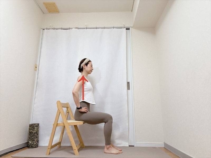 両手を腰に添え、背筋を伸ばして椅子に座った体勢