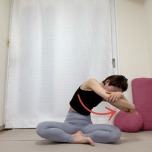 あぐらで座り体の前で両肘を抱え、背骨を丸めながら肘を右に引いた体勢