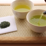 急須で湯呑みに注がれる緑茶と茶葉