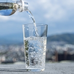 屋外でペットボトルからグラスに注がれる炭酸水