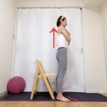 両手を胸の前でクロスし、椅子の前に立った体勢