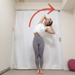 頭の後ろで手を組み、脇を開いて立ち、上体を右に倒した月のポーズ