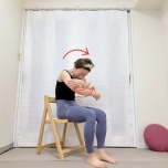 椅子に座り、背中を丸めて胸の前で両手をクロスした体勢