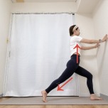 両手を壁につき、右膝を曲げ、左脚を後ろに引いて脚の付け根を伸ばす腸腰筋のストレッチ