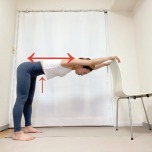 椅子の背もたれに手を置いて後ろに歩いて背中を伸ばすストレッチ