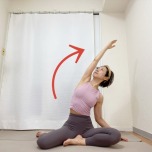 右脚を前にした横座りの体勢から左手を引き上げて体を右に倒した体側のストレッチ