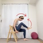 椅子に座り、上体を前にかがめながら左膝を胸に寄せた体勢