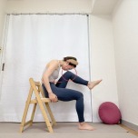 椅子に座り、上体を前にかがめ、左膝と鼻先を寄せた体勢