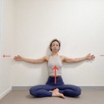 壁を背にしてあぐらで座り、両手を肩の高さに開いた体勢