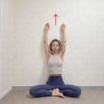 壁を背にしてあぐらで座り、両手をバンザイした体勢