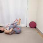 仰向けになり、膝裏を抱えて胸に膝を寄せ、左右に腰を揺らすストレッチ