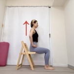 手を腰に添え、椅子に浅く座った体勢