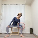 脚を大きく開いて椅子に座り、右腿に肘をついて上体を軽く右に傾けた体勢