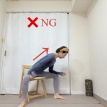 脚を大きく開いて椅子に座り、右肘を腿に乗せ、背中を伸ばして行うNGストレッチ