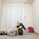 仰向けで軸足の腿裏にタオルを通して胸に寄せた針の糸通しのポーズ