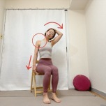 椅子に座り、左腕を体側に、頭を右に傾けて右手をこめかみに添えた首のストレッチ