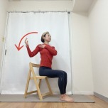 椅子に座り、右手を鎖骨下、左手を斜め後ろに引き上げ、脇を締めて肘を曲げる前鋸筋のエクササイズ