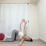 四つ這いで左脇の下に右腕を通し、左手を天井に引き上げたキャットストツイストポーズ