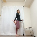 椅子の背もたれに右手を添えて立ち、左膝を曲げて脚の甲を掴んでかかとをお尻に引き寄せた体勢