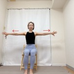 椅子に座り、手の甲を前に向けて両手を肩の高さで開いた体勢