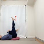 お尻の下にクッションを敷いて膝を抱えた仰向けから左脚を天井に伸ばした体勢