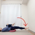 お尻の下にクッションを敷いた仰向けから右膝を抱え、左脚を伸ばした腸腰筋のストレッチ