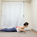 タオルの端を持ち、両手を頭の上に伸ばしたうつ伏せかわ、肘を曲げて胸に引き寄せた背中のエクササイズ