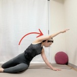 膝を立てて座っり、右手を後ろの床に着いて左手を引き上げ、両膝を右に倒して後ろを振り返って左腰から体側を伸ばすストレッチ