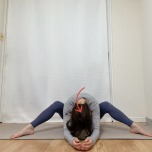 脚を広めに開いて膝を立てて座り、背骨を緩めて前屈した体勢