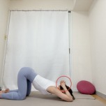 両手を組んで肘をついた四つ這いから組んだ両手を頭の後ろに添え、おでこを床に下す肩回りのストレッチ
