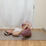 仰向けで両膝を抱え、膝を外に開いて両手でつま先を抱えた体勢