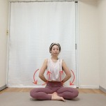 あぐらで座り、肘を曲げて軽く握った手を腰に添え、肩甲骨から腕を動かして前後に回す肩甲骨はがしエクササイズ