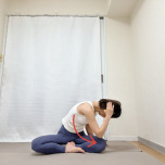 左手を後頭部に添えたあぐらで座り、背骨を丸め名がrあ左肘を右膝に寄せるツイストエクササイズ