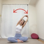 あぐらで座り、両手を組んで頭上に引き上げて左右にしならせる背骨のストレッチ