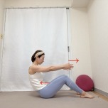 両膝を立てて座り、両手を体の前に伸ばし、お腹を引き込みながら背骨を丸めるエクササイズ
