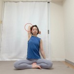 左肘を曲げて高く引き上げ、腕を耳の横に近づけて脇を大きく開いてあぐらで座った体勢